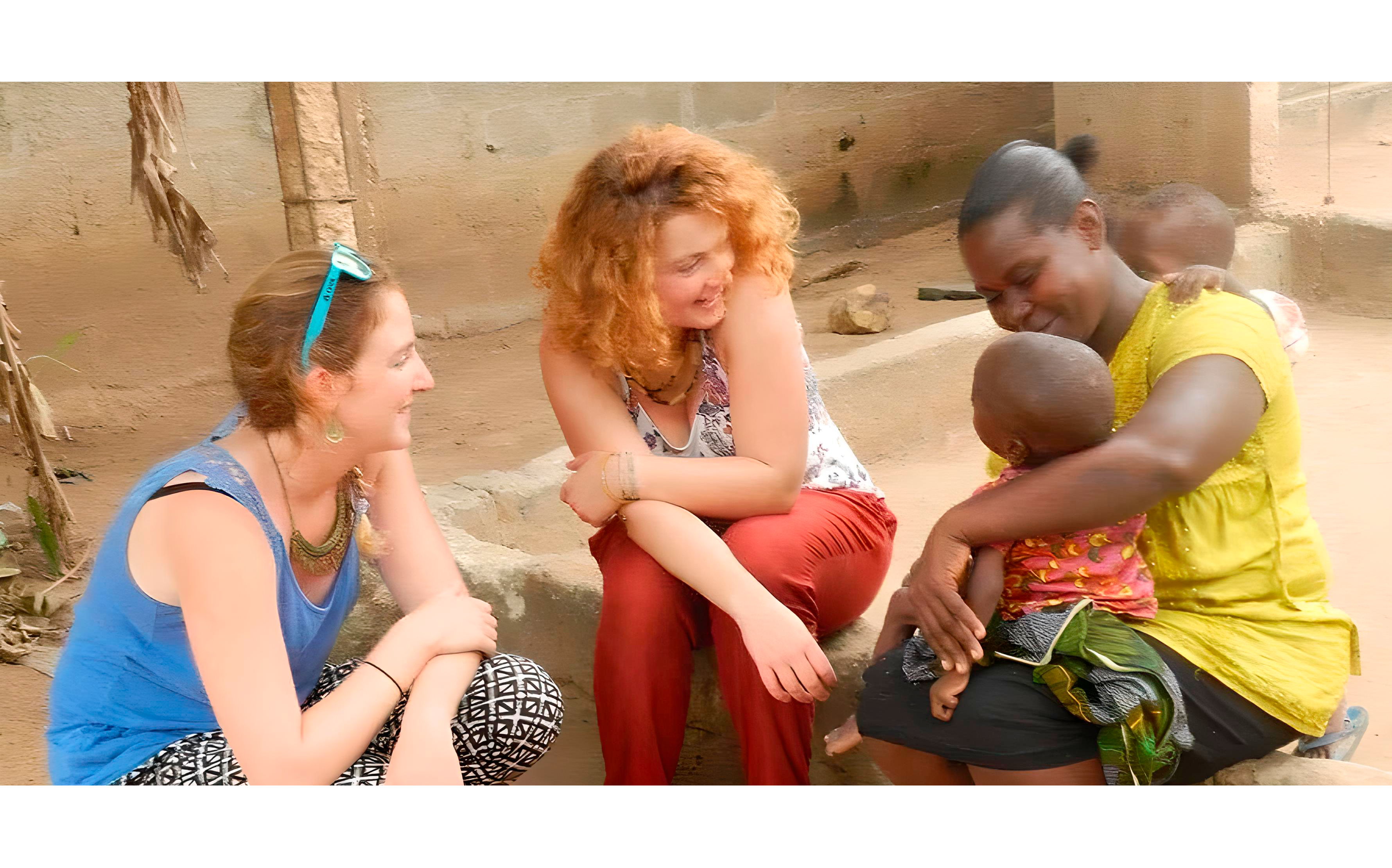 Image de deux benevoles regardants une habitante du Togo porter son bébé